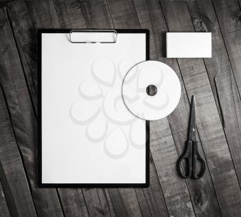Photo of blank corporate stationery on wood table background. Blank paper, clipboard, business card, cd and scissors. Top view.
