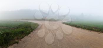 Gravel road in the fog. Rural landscape. Panorama shot.