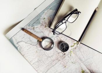 Stationery, travel accessories and vacation items. Vintage toned image. Flat lay. Top view. Map, notebook, magnifier, compass glasses and pencil