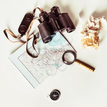 Travel still life. Map, binoculars, compass, magnifier and crumpled paper. Vintage toned image. Top view. Flat lay.