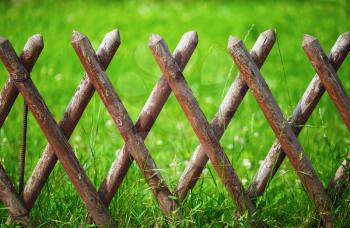 Brown timber wooden fence on a green lawn background.