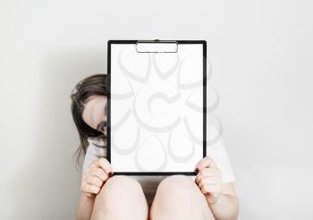 Woman holding clipboard with a blank paper. Blank paper poster with plenty of copy space in female hands.