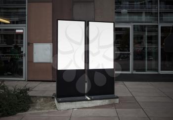 Two blank white vertical lightboxes in a city. Mock up of street posters.