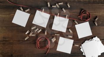 Blank frames of photo, rope and clothespins on wood background. Flat lay.