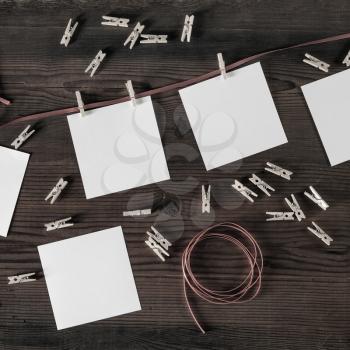 Blank photo paper, rope and clothespins on wood background. Responsive design mockup. Flat lay.
