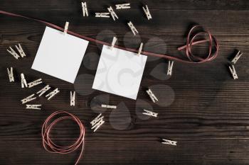Blank frames of photo. Photo paper, rope and clothespins on wood table background. Flat lay.