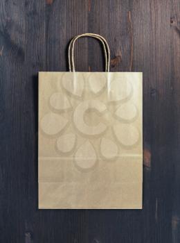 Blank craft paper bag on wood table background. Responsive design mockup. Flat lay.