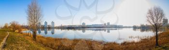 Panoramic shot of large lake. Coastline, the reflection of buildings in calm water.
