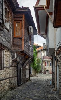 Nesebar, Bulgaria - September 08, 2014: Narrow street of the old town of Nessebar. Retro houses and cobblestone pavement. UNESCO world heritage site. Vertical shot.