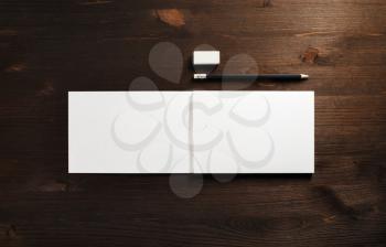 Blank booklet, pencil and eraser on wooden background. Responsive design mockup. Flat lay.