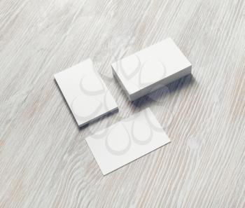 Blank white business cards with soft shadows on light wooden background. For design presentations and portfolios.