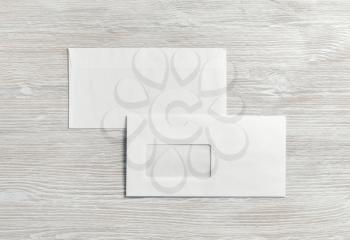 Photo of two blank paper envelopes on light wooden background. Back and front. Flat lay.