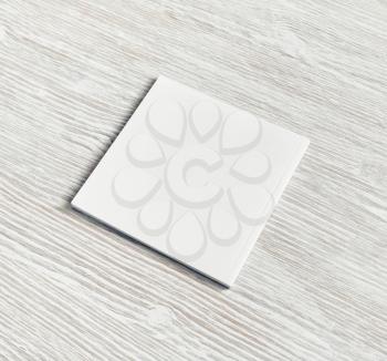 Blank square notebook on light wood table background. White paper notepad.