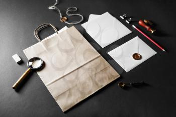 Blank paper bag, envelopes and retro stationery on black paper background.