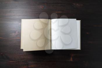 Photo of opened blank square book on wooden background. Template for design presentations and portfolios. Flat lay.