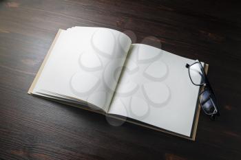 Blank book and glasses on wood table background. Template for branding design.