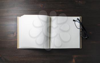 Blank booklet and glasses stationery on wood table background. Responsive design mockup. Flat lay.