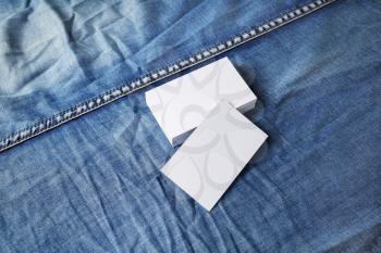 Photo of blank white business cards on denim background. For design presentations and portfolios.