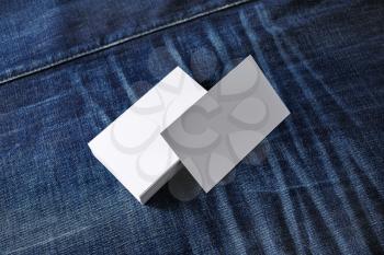 Photo of blank white business cards on denim background. For design presentations and portfolios.