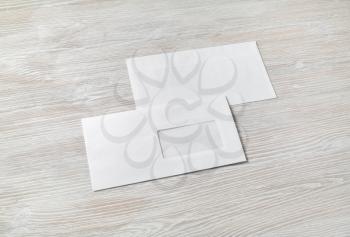 Photo of two blank envelopes on light wooden background. Back and front. Template for branding identity.