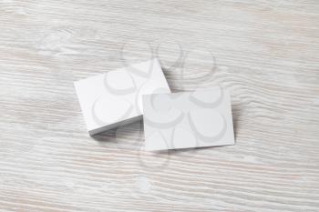 Photo of blank white business cards with soft shadows on light wooden background. For design presentations and portfolios.