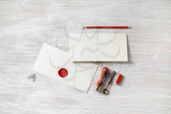 Vintage letter envelope with wax seal, stamp, pencil, spoon and postcard on light wooden background. Mock-up for your design. Flat lay.