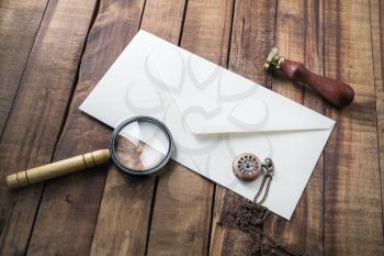 Photo of blank envelope, magnifier, stamp and clock on wooden background. Vintage stationery.