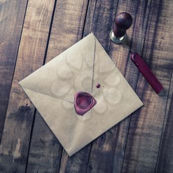 Photo of vintage craft paper envelope, seal, stamp and magnifier on wooden background. Top view.