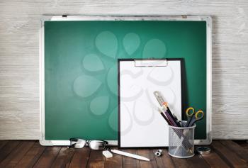 Photo of blank green blackboard and stationery. School supplies. Responsive design template.