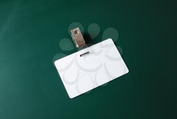 Blank ID card. White plastic badge on green blackboard background. Copy space for text. Responsive design template.