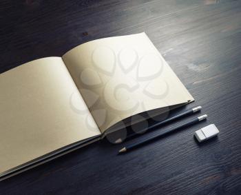 Photo of blank kraft paper booklet, pencils and eraser on wood table background.