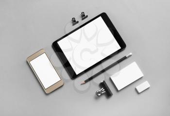 Gadgets with blank screens and stationery on gray paper background. Template for placing your design. Top view.