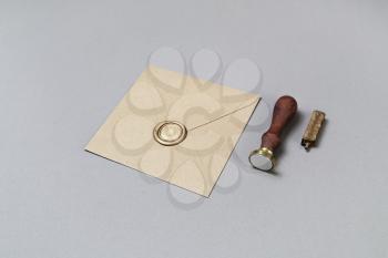 Craft paper envelope with wax seal and stamp on gray paper background.