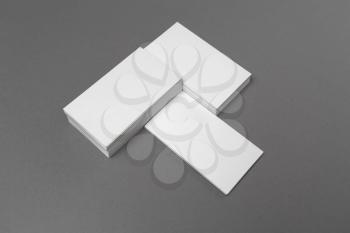 Photo of blank white business cards with soft shadows on gray paper background. Mock-up for ID. Studio shot.