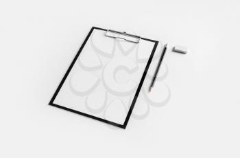 Clipboard with blank letterhead, pencil and eraser on white paper background. Blank stationery template with plenty of copy space.