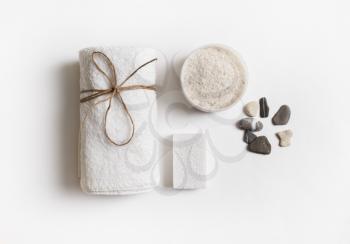 Beauty and spa concept. Towel, sea salt, pumice and stones on white paper background. Flat lay.