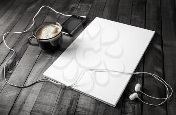 Photo of blank stationery. Responsive design mockup on wooden background. Letterhead, coffee cup, smartphone and headphones.