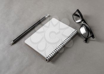 Blank notepad, glasses and pencil on craft paper background. Stationery elements. Responsive design mockup.