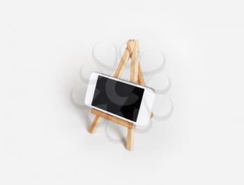 Photo of mobile phone with blank screen on wood holder at white paper background.
