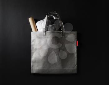 Blank gray fabric shopping bag on black paper background. Flat lay.