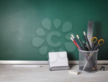 Blank school stationery over green blackboard background. Education concept.
