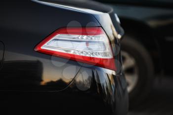 Car headlight. Back light of city car on blurred black background