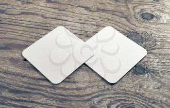 Two blank beer coasters on wooden background. Responsive design mockup.