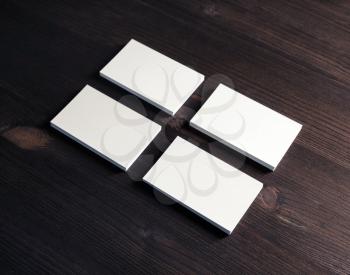 Four stacks of blank business cards on dark wooden background. Mockup for branding identity.