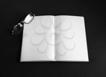 Blank open book and glasses on black background. Responsive design mockup.