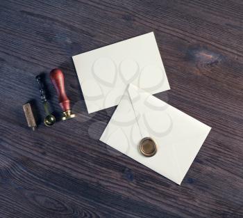 Blank paper envelopes with golden wax seal, stamp, spoon and postcard on wooden background. Mockup for your design. Flat lay.