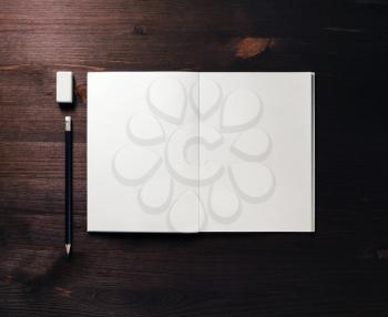Pencil, eraser and notepad on dark wooden background. Flat lay.