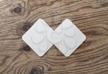 Two blank white beer coasters on vintage wooden table background. Responsive design mockup. Flat lay.