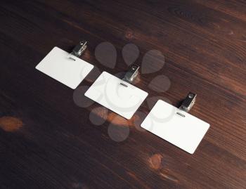Three blank badges on vintage wooden background. Blank plastic id cards. Top view. Flat lay.