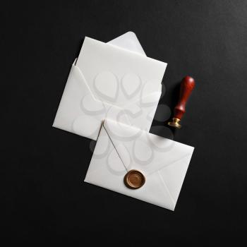 Vintage envelope with golden wax seal, stamp and postcard on black paper background. Flat lay.